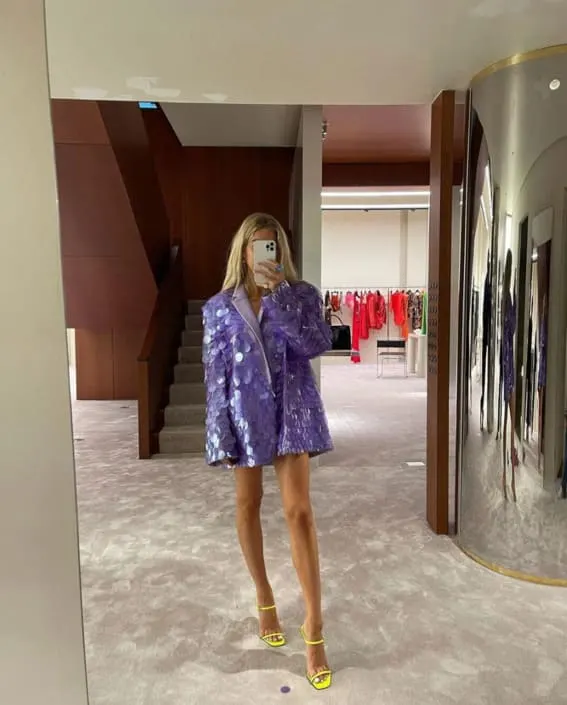 A stylish selfie in the mirror featuring a playful purple sequin blazer, perfectly matched with vibrant yellow strappy heels.