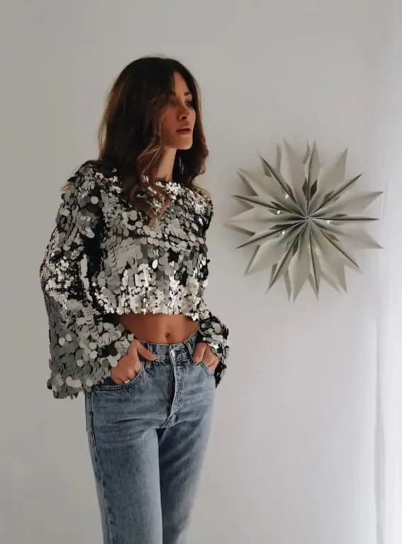 Outfit showcasing a cropped sequined blouse with relaxed denim, blending casual comfort with festive sparkle.