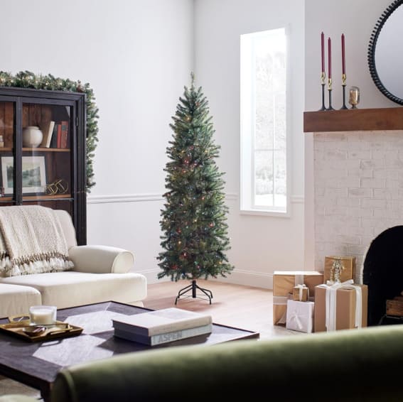 A 6.5-foot National Tree Company artificial pre-lit slim Christmas tree with multicolor lights and stand, styled in a modern living space.