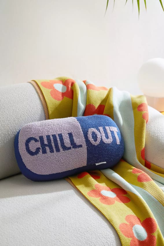 Chill Pill Shaped Throw Pillow on sofa with colorful throw blanket in living room
