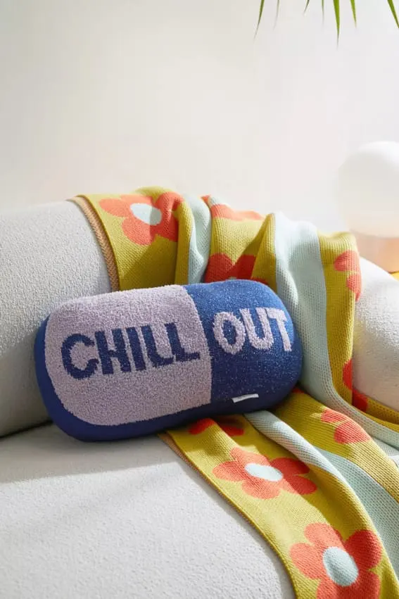 Chill Pill Shaped Throw Pillow on sofa with colorful throw blanket in living room