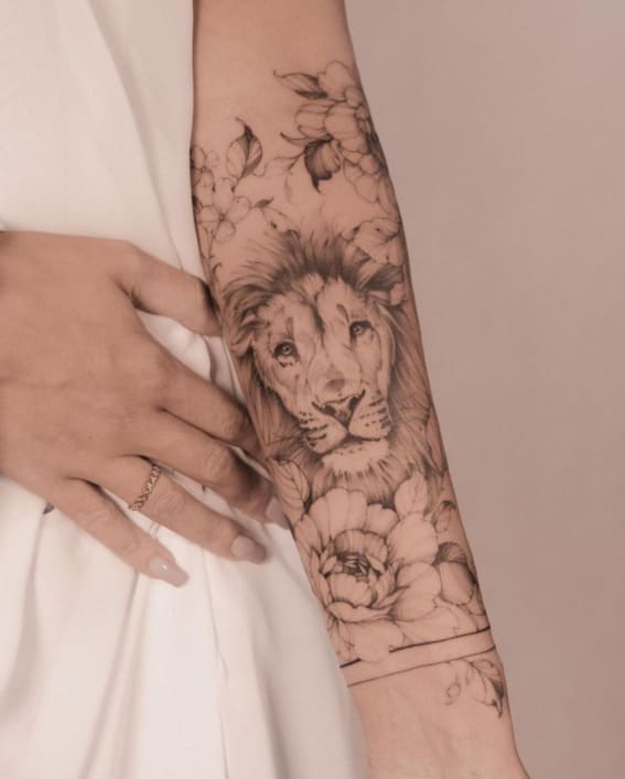 A detailed lion tattoo with floral elements on a person's arm.
