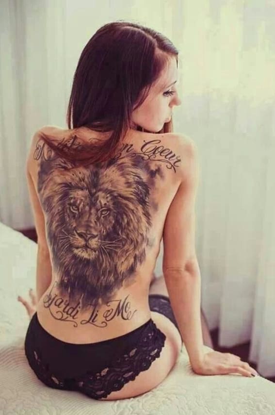 A large and detailed lion tattoo on a person's back with a script
