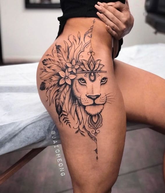 An intricate lion tattoo adorned with flowers on a person's thigh.