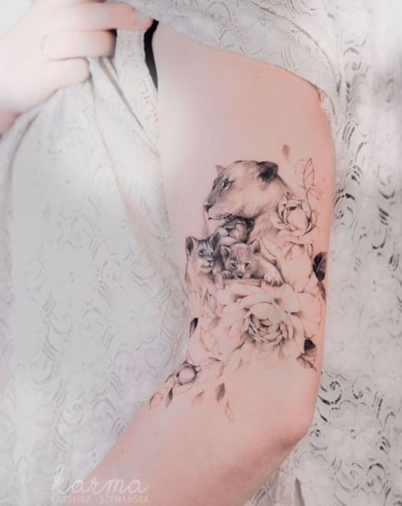 A lioness and cubs tattoo enveloped in floral patterns on a person's side.