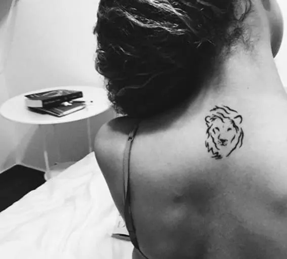 A minimalistic lion tattoo on the back of a person's shoulder