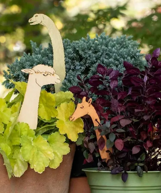 Whimsical animal stakes peeking out from lush plants.