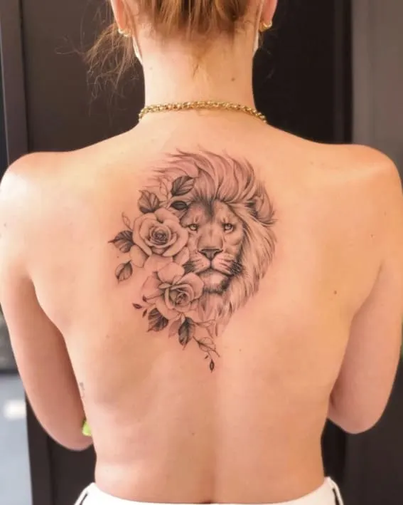 A lion surrounded by roses tattoo on a person's back