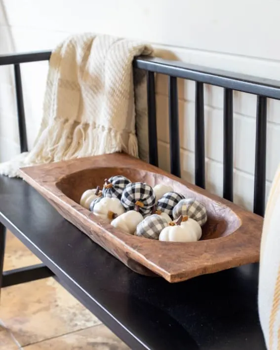 A dough bowl on a bench displaying checkered pumpkins