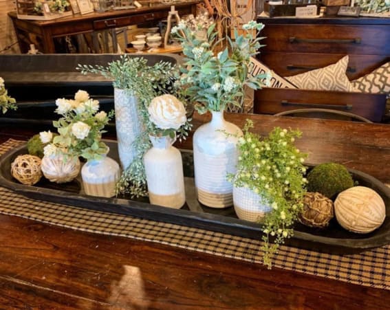 Dough bowl on a table displaying a collection of patterned vases and greenery