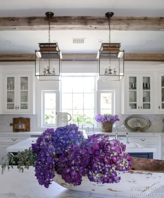 Dough bowl centerpiece filled with lush purple hydrangeas on a kitchen island.