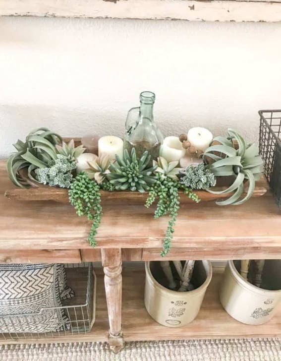 Dough bowl styled with an assortment of succulents and candles on a table