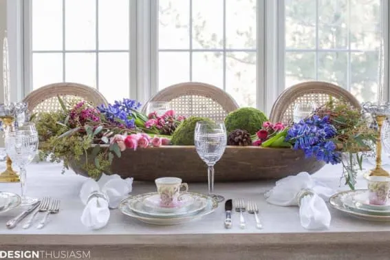 Dough bowl on a dining table with vibrant flowers and moss spheres
