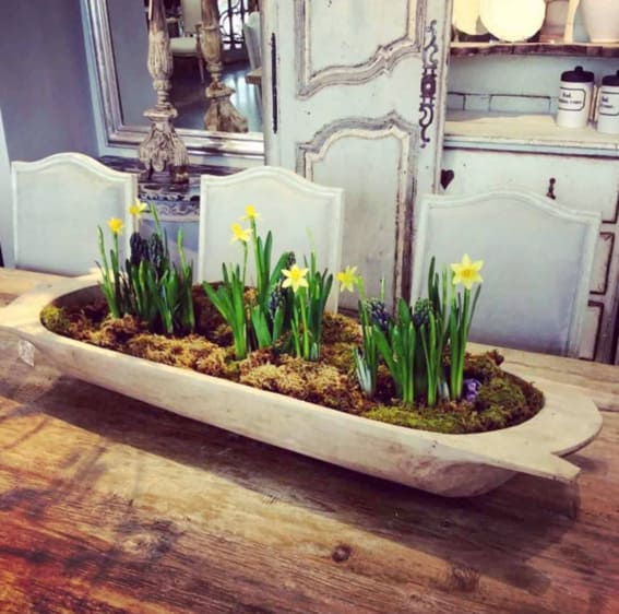 Dough bowl on a rustic table showcasing blooming daffodils and hyacinths
