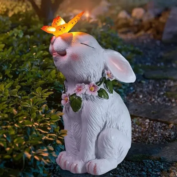 Solar-powered garden statue of a rabbit with a light-up butterfly, outdoor decor.