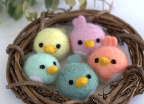Set of five pastel-colored felt chicks in a natural twig nest.