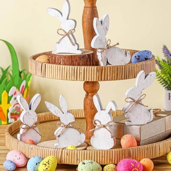 Six rustic wooden bunny signs displayed on a tiered tray among Easter eggs.