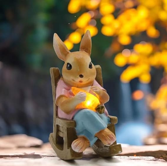 A miniature rabbit figurine sitting on a rocking chair holding a glowing orb.