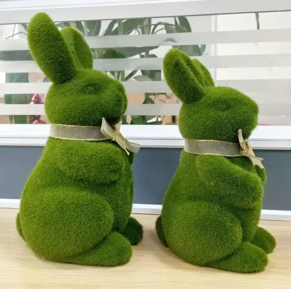Two green moss-covered bunny sculptures with bows, Easter decor.