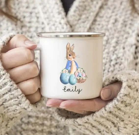 A cozy hand holding a personalized Easter Peter Rabbit mug with the name 'Emily'.