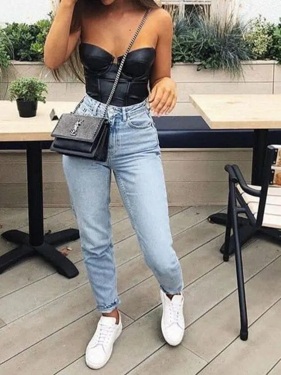 Woman in a black bodysuit with fringed accessories and ripped jeans.