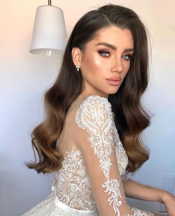 Bride with long hair and soft waves in a lace-embroidered dress.