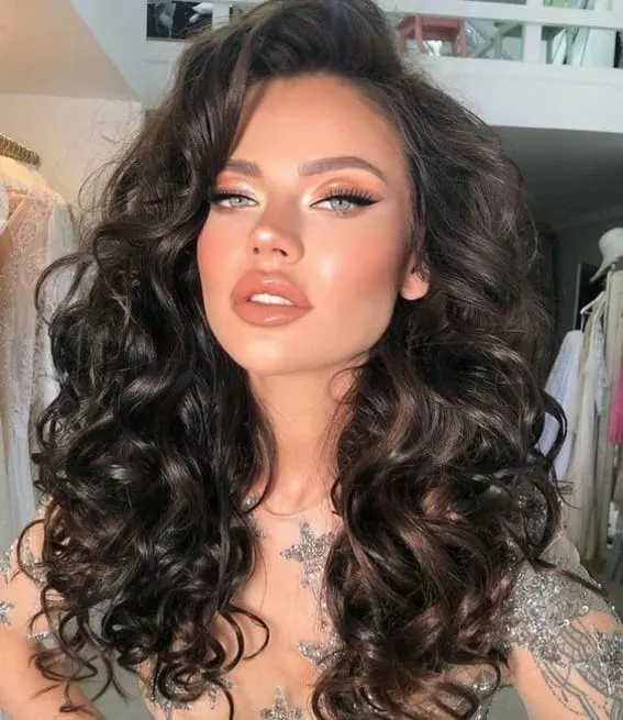 Woman with deep, gorgeous brunette curls and glam makeup.