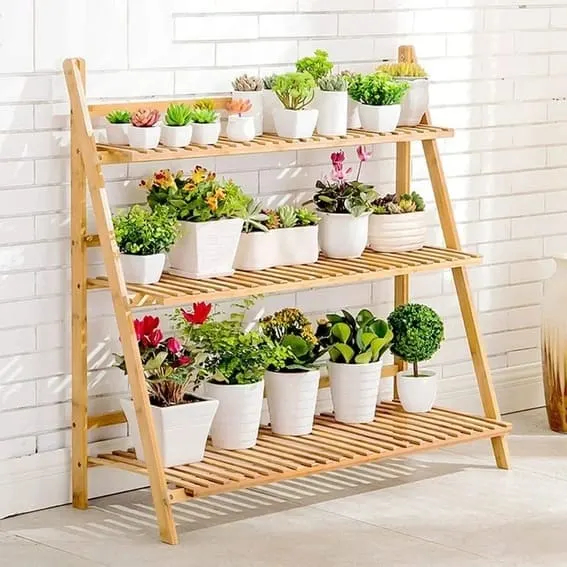 Light wooden A-frame plant shelf with an array of succulents and flowers in white pots.
