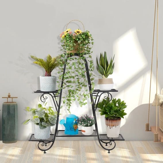 Black metal outdoor garden shelf adorned with lush plants and decorative watering can.