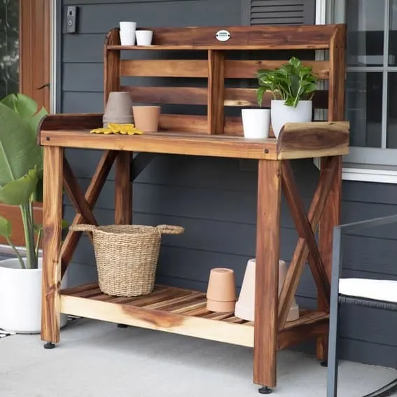 Wooden outdoor gardening shelf with plants and a woven basket on a home porch.
