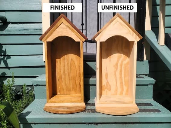 Birdhouse-style garden shelf mounted on a wooden fence.