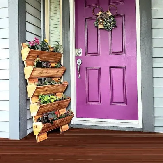 Five-tier wooden outdoor garden shelf with a variety of colorful flowers.