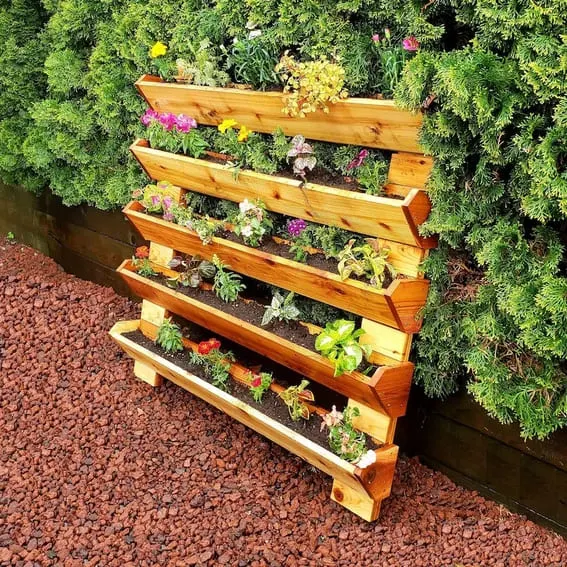 Five-tier wooden outdoor garden shelf with a variety of colorful flowers.