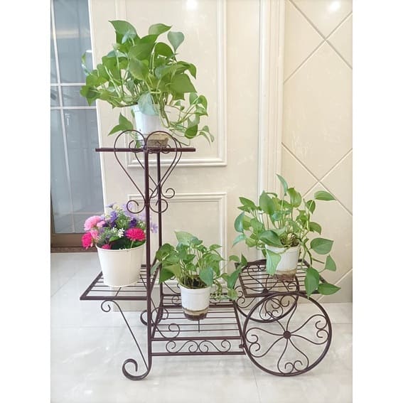 Elegant wrought iron garden shelf with a variety of potted plants indoors.
