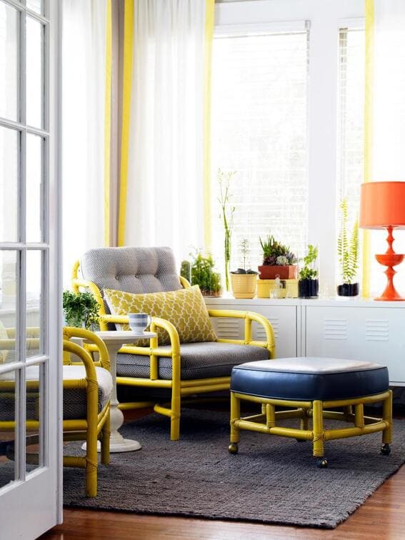 A vibrant sunroom corner with yellow and gray furniture, white curtains accented with yellow stripes, and a pop of greenery.