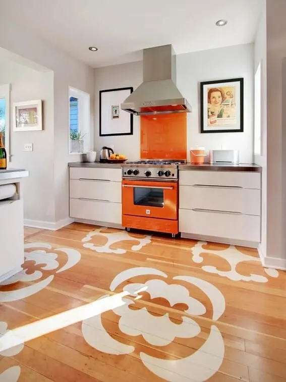 Modern kitchen with orange range and stenciled hardwood floors.