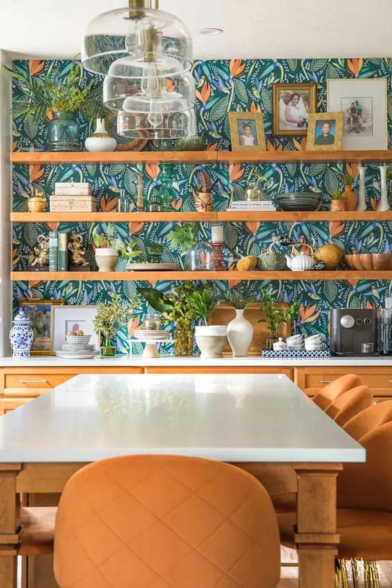 Maximalist kitchen with graphic wallpaper and burnt orange velvet chairs.