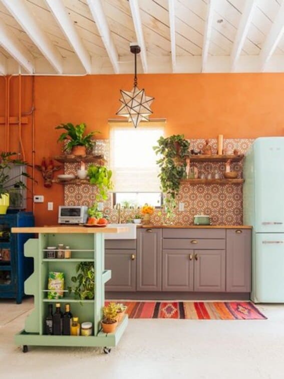 Boho kitchen with orange walls, patterned tile backsplash, and colorful decor.