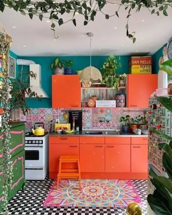 Eclectic kitchen with orange cabinets, multicolored tiles, and vibrant decor.