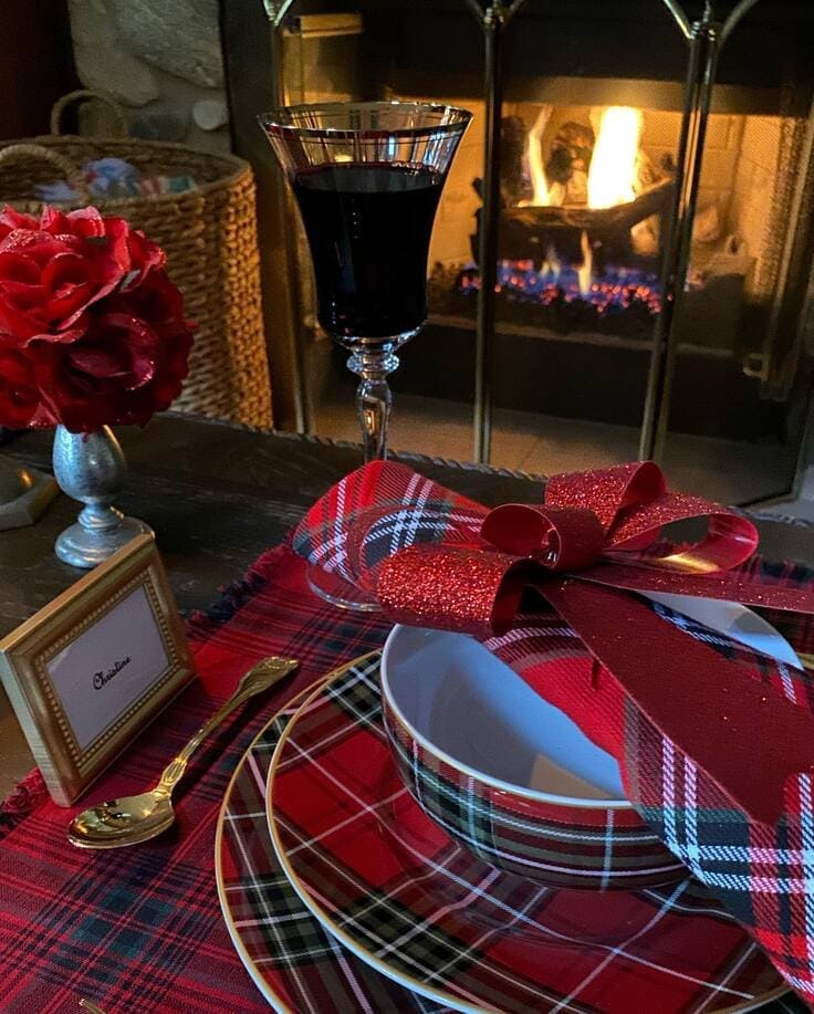 Fireside Ralph Lauren place setting—tartan plates and placemat, red glitter-bow napkin, crystal wine glass, gold flatware.