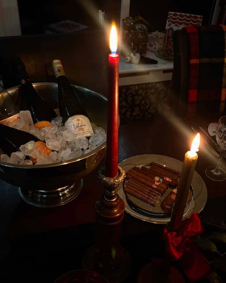 Ralph Lauren Christmas bar vignette—silver champagne bucket on ice, red taper candles in brass, cigar plate, tartan throw in the background.