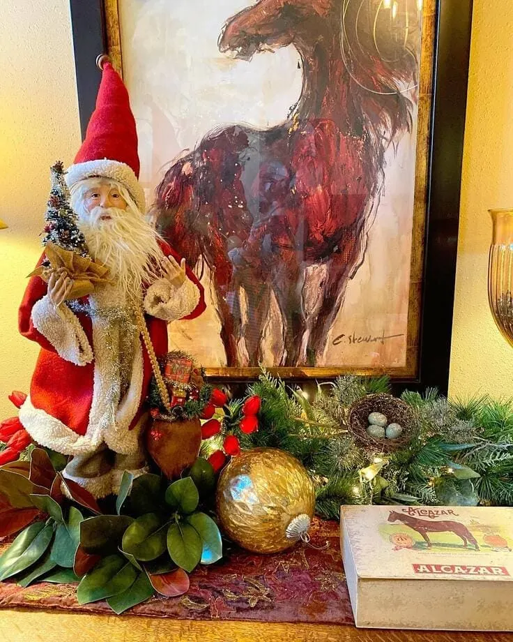 Ralph Lauren Christmas vignette—vintage Santa, bold equestrian horse art, magnolia leaves and cedar garland, gold ornament, bird nest, Alcazar horse box.