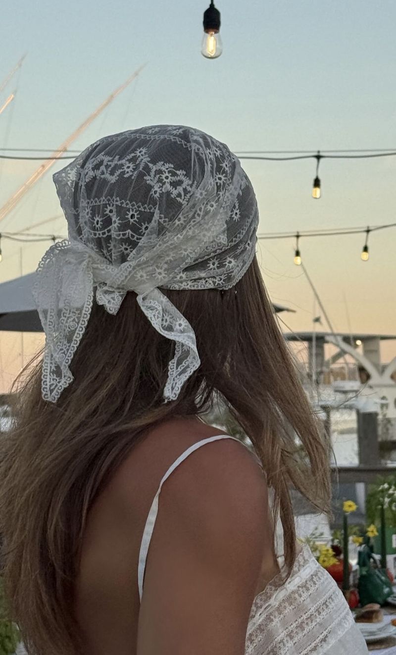 Woman wearing a white lace headscarf by the water