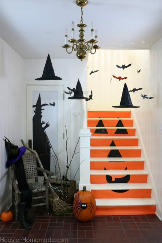 Indoor staircase decorated with orange jack-o'-lantern risers and black bat wall decals