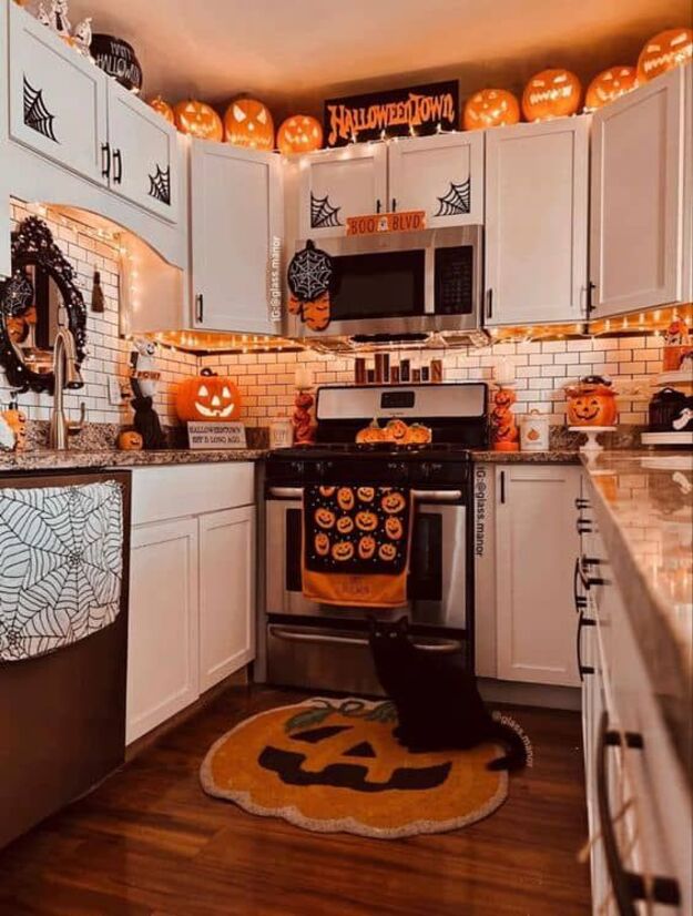 Cozy Halloween kitchen with lit jack o lantern decor, spiderweb accents, and orange lights