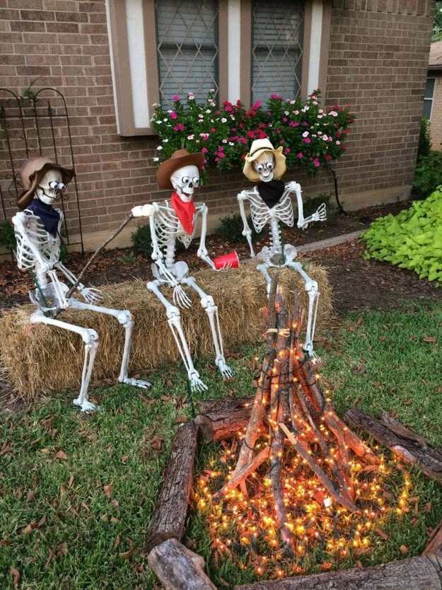Outdoor Halloween yard decor with skeletons sitting around a glowing campfire