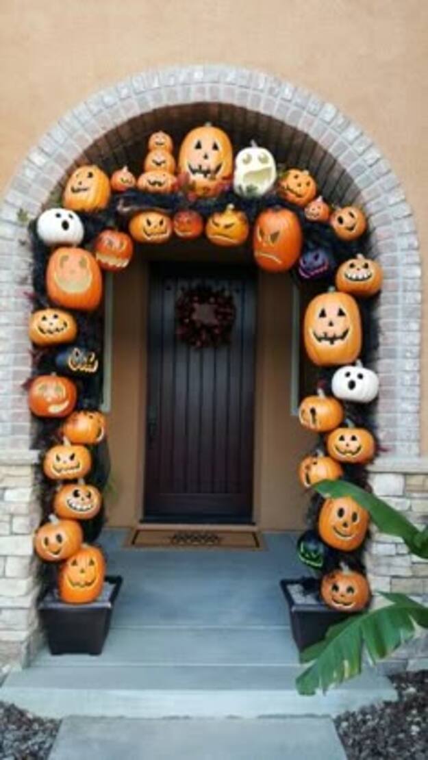 Front porch arch covered in smiling jack o lantern pumpkins around a dark front door
