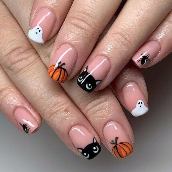 Cute Halloween nails with tiny ghosts, pumpkins, black cats, and little spiders on a glossy nude pink base