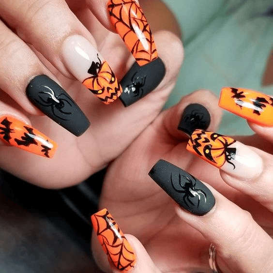 Orange and black Halloween nails with spider web art, pumpkin face design, bat accents, and raised spider details