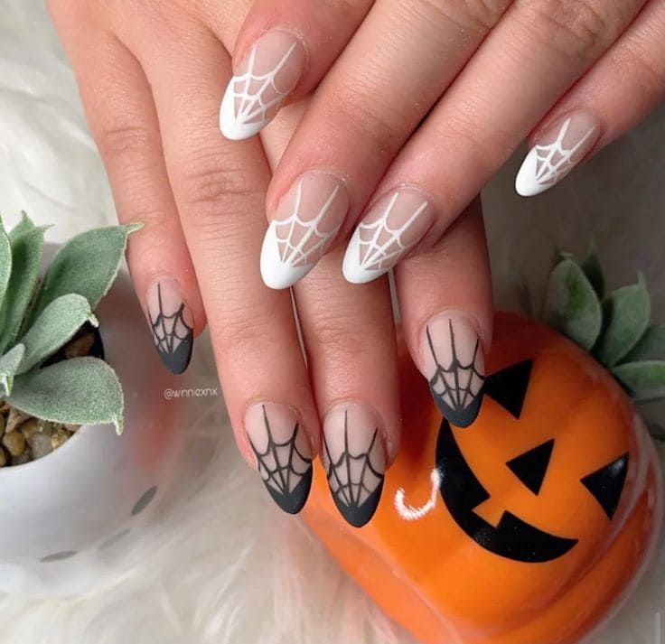 Halloween French tip nails with white and black spider web designs on nude almond shaped nails